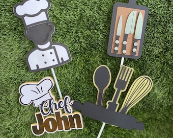 May include: Four cake toppers featuring a chef, a chopping board with knives, a rolling pin with a spoon, fork, and whisk, and a chef hat with the text "Chef John".