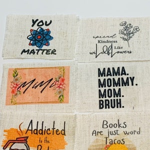 May include: Six fabric patches with different sayings and designs. The patches are beige with black text and colorful illustrations. The sayings include "You Matter", "Spread Kindness Like Wildflowers", "Mimi", "Mama. Mommy. Mom. Bruh.", "Addicted to the Pot", and "Books Are Just Word Tacos".