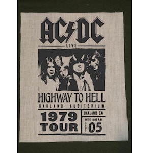May include: A black and white AC/DC "Highway to Hell" tour poster from 1979. The poster features the band's name, "AC/DC", above a black and white image of the band members. The poster also includes the tour name, location, and date.