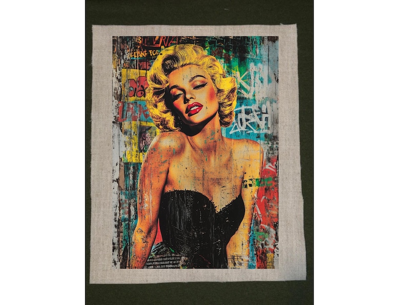 May include: A pop art style portrait of Marilyn Monroe with blonde hair and red lipstick. She wears a black strapless top. The background is a collage of graffiti and colorful paint splatters, with some text visible.
