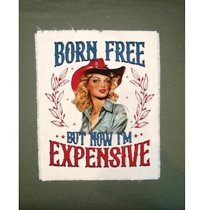 May include: A rectangular patch with a vintage illustration of a woman in a cowboy hat. The text "BORN FREE BUT NOW I'M EXPENSIVE" is displayed in blue and red, with decorative elements.