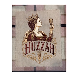 May include: A rectangular fabric patch featuring a printed illustration of a queen wearing a crown and holding a goblet. Below the figure, the word HUZZAH is printed in large, dark red letters, accompanied by an ornate gold goblet graphic.