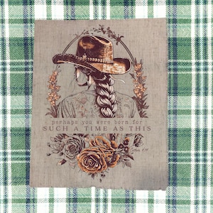 May include: A rustic print featuring a woman with a braided hairstyle wearing a cowboy hat. The image includes floral accents and the text "perhaps you were born for such a time as this". The artwork is set against a plaid background.