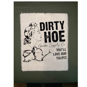 May include: A black and white sign with the text "DIRTY HOE" and "Garden Supply Co." A vintage illustration of a woman with a watering can and bucket is featured. The sign also says "YOU'LL LOVE OUR TULIPS!"