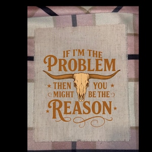 May include: A tan fabric patch with the text "IF I'M THE PROBLEM THEN YOU MIGHT BE THE REASON" in brown lettering. A steer skull graphic is centered below the word "PROBLEM". The patch has a frayed edge.