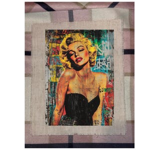 May include: A framed art print featuring a pop art style portrait of Marilyn Monroe. The artwork showcases Monroe with blonde hair, red lips, and a black strapless top, set against a backdrop of colorful graffiti.