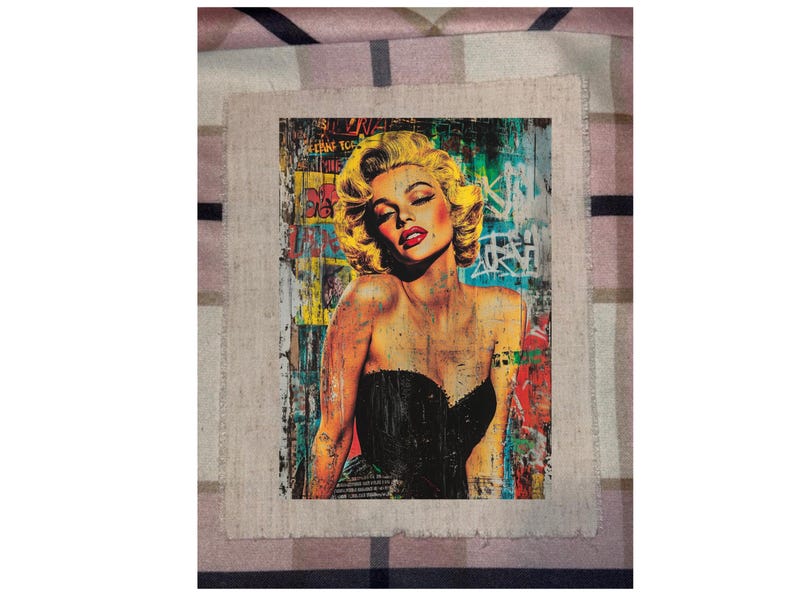 May include: A framed art print featuring a pop art style portrait of Marilyn Monroe. The artwork showcases Monroe with blonde hair, red lips, and a black strapless top, set against a backdrop of colorful graffiti.
