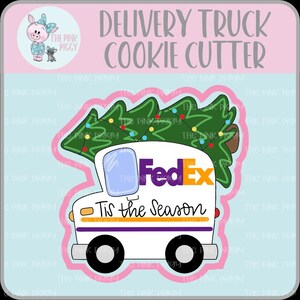 May include: A white delivery truck cookie cutter with the FedEx logo and a Christmas tree on top. The text "Tis the Season" is written on the side. The cutter is in a pink and blue frame.