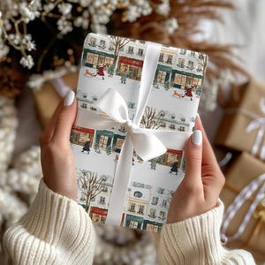 a woman holding a wrapped present in front of a christmas tree