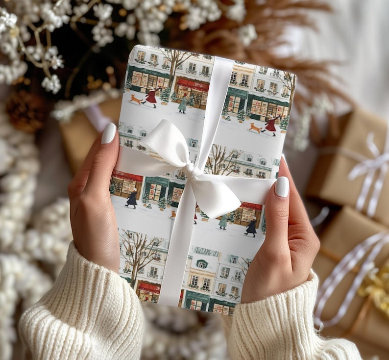 a woman holding a wrapped present in front of a christmas tree