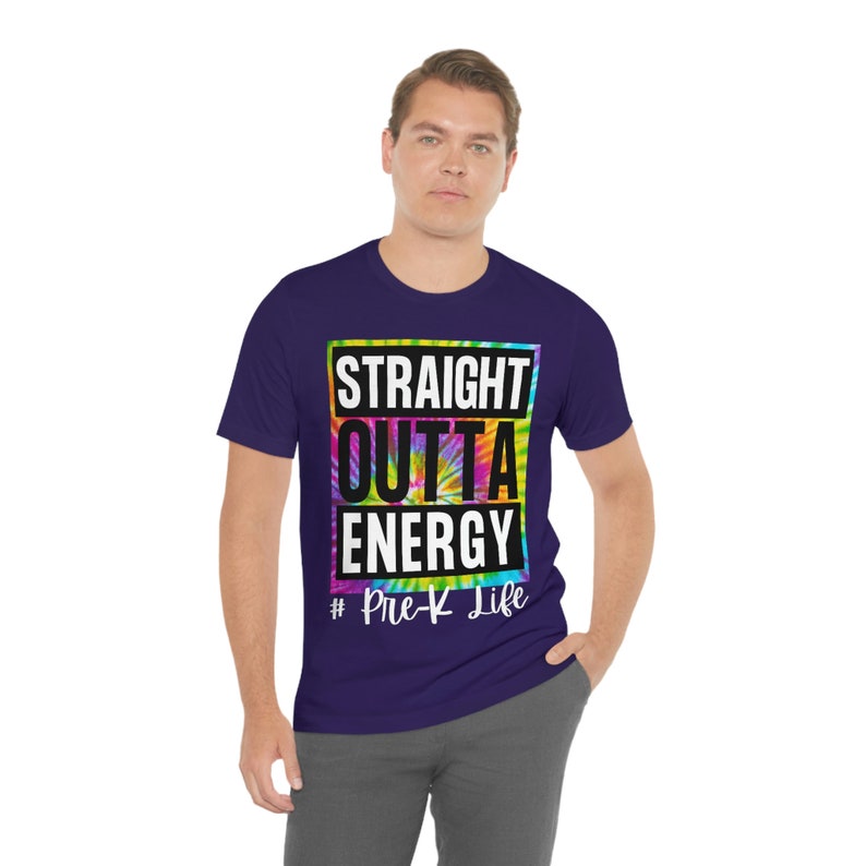 Pode incluir: Uma camiseta roxa com um design tie-dye e o texto "Straight Outta Energy #Pre-K Life" em preto.