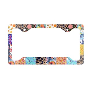 May include: A colorful license plate frame with a patchwork design featuring various floral patterns in shades of blue, pink, yellow, and green.