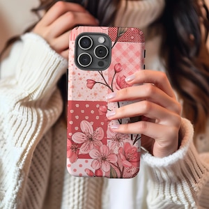 Può includere: Una custodia per telefono rosa e rossa con fiori e design patchwork. La custodia ha un ritaglio per l'obiettivo della fotocamera e un motivo floreale.