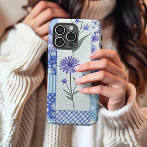 May include: A blue and white floral phone case with a patchwork design. The case has a camera lens cutout and a floral pattern.