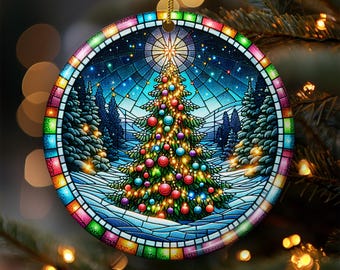 Puede incluir: Adorno navideño redondo con diseño de vidriera. El adorno presenta un árbol de Navidad decorado en un paisaje nevado, rodeado de árboles de hoja perenne. El borde es un mosaico colorido. Se adjunta una cuerda dorada para colgar.
