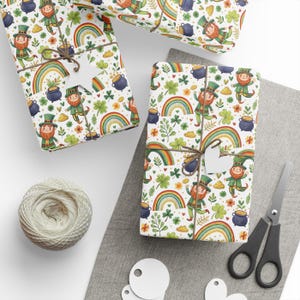 May include: White wrapping paper with a repeating pattern of leprechauns, rainbows, shamrocks, and pots of gold. The paper is wrapped around a gift box with a green ribbon and a white star.
