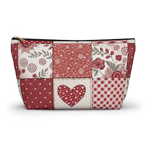 Puede incluir: Bolsa de cosméticos de patchwork rojo y blanco con un diseño de corazón. La bolsa tiene una cremallera y un forro negro.