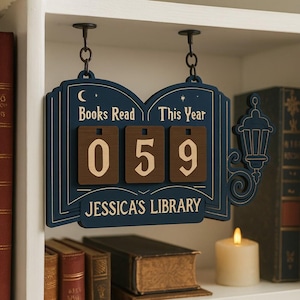 May include: A navy blue wooden sign with the words "Books Read This Year" and "Jessica's Library." The sign displays the number "059" on brown number blocks. A decorative lantern and books are visible.