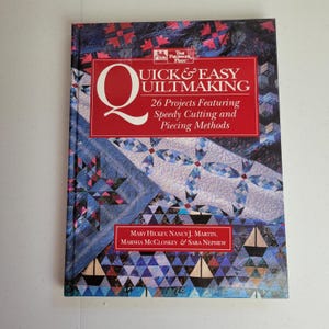 Puede incluir: Un libro titulado "Quick & Easy Quiltmaking" con una pancarta roja y texto blanco. La portada presenta un patrón de edredón azul y blanco. El libro es de Mary Hickey, Nancy J. Martin, Marsha McCloskey & Sara Nephew.
