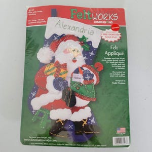 May include: Felt applique Christmas stocking kit featuring a Santa Claus design. The kit includes pre-sorted sequins, wool and acrylic yarns, cotton thread, printed felt, beads, and instructions. The stocking measures 18 inches (46 cm) long.