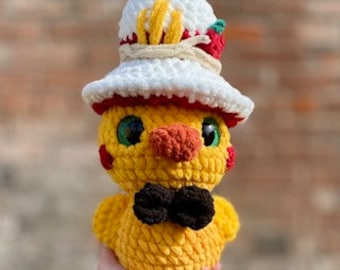 May include: A yellow crocheted chick toy wearing a white crocheted hat with red and white spaghetti and a tomato on top. The chick also has a black bow tie.