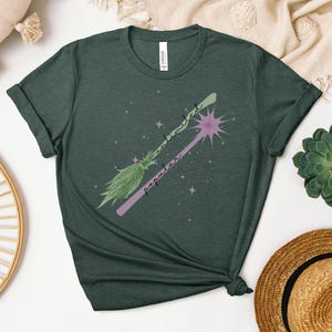 May include: A green t-shirt with a pink and green broom and the text "un-medicated popular" on it.
