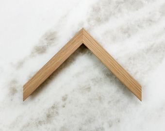 May include: A wooden picture frame with a simple, angled design. The frame is made of natural wood with a light brown finish.
