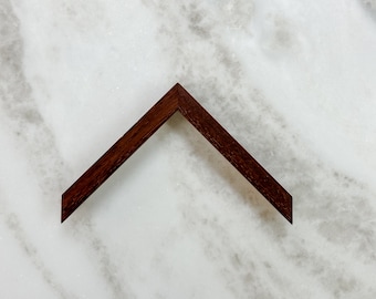 May include: A dark brown wooden picture frame corner with a mitered edge.