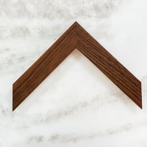 May include: A dark brown wooden picture frame with a simple, angled design.