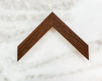 May include: A dark brown wooden picture frame with a simple, angled design.