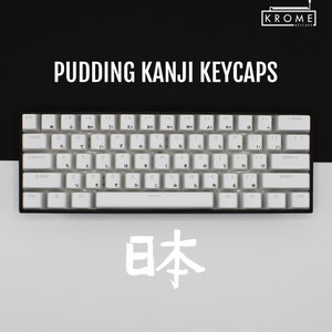 May include: White keyboard with Japanese characters on the keys. The keyboard has a black frame and a white space bar. The word "日本" is written in white on a grey background.