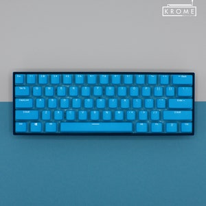 May include: A compact, blue mechanical keyboard with white lettering. The keyboard has a black frame and a variety of keys, including letters, numbers, and function keys. The brand name "KROME KEYCAPS" is visible in the upper right corner.