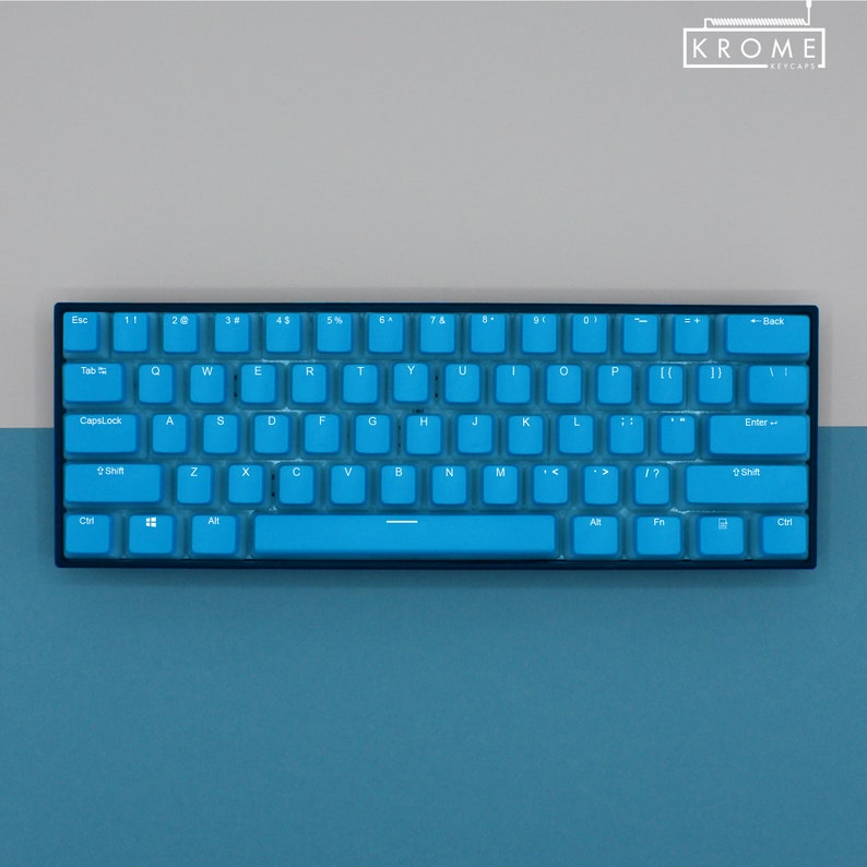 May include: A compact, blue mechanical keyboard with white lettering. The keyboard has a black frame and a variety of keys, including letters, numbers, and function keys. The brand name "KROME KEYCAPS" is visible in the upper right corner.