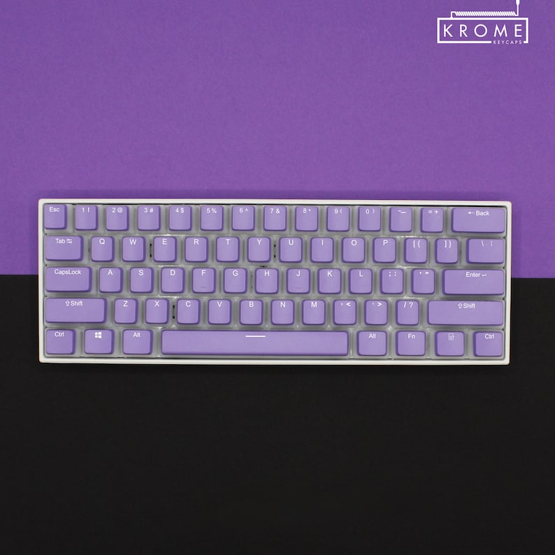 May include: A compact, white-framed keyboard with lavender keycaps. The keys are arranged in a standard layout, with letters, numbers, and symbols. The keyboard is set against a two-tone background of purple and black, with the brand name "KROME KEYCAPS" in the top right corner.