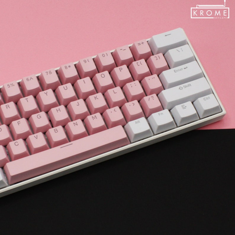May include: A white and pink mechanical keyboard with a pink space bar and white keys with black lettering. The keyboard has a pink background and the text "KROME KEYCAPS" is in the top right corner.