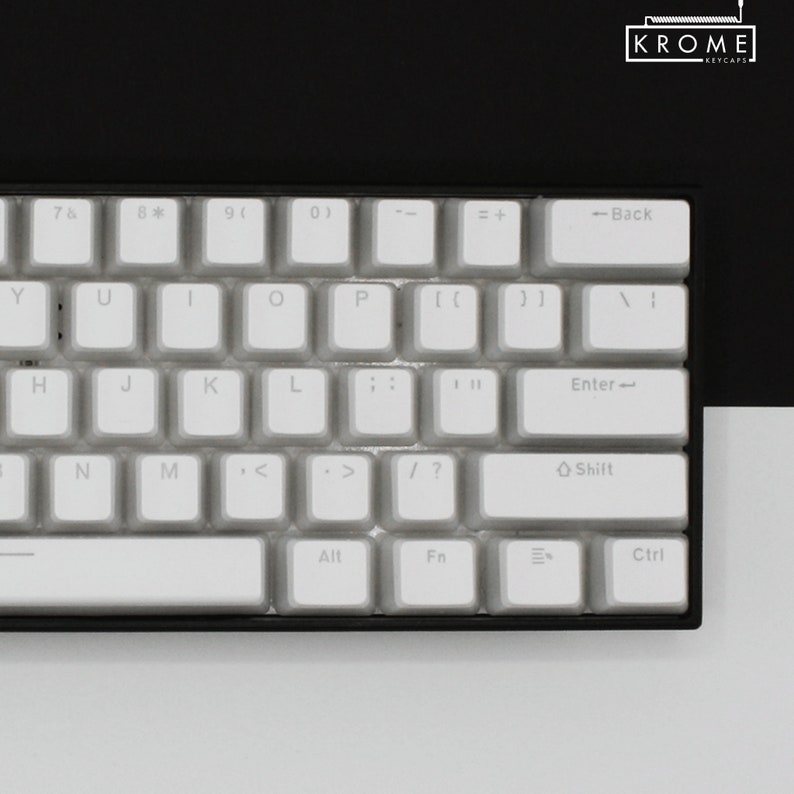 May include: A white mechanical keyboard with a black frame. The keyboard has a standard layout with keys labelled 7, 8, 9, 0, Y, U, I, O, P, H, J, K, L, ;, ', N, M, <, ., >, /, ?, Shift, Enter, Back, =, +, Alt, Fn, Ctrl. The keyboard is on a white surface.