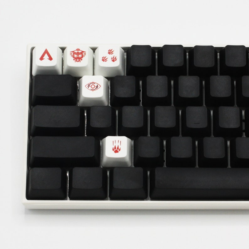 May include: A white mechanical keyboard with black keys and five custom keycaps. The keycaps have red symbols, including a triangle, a spaceship, paw prints, an eye, and a paw print.
