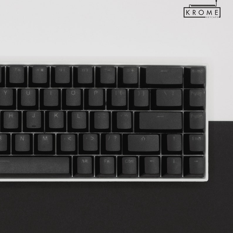 May include: A black mechanical keyboard with white keycaps and a white frame. The keyboard has a standard layout with function keys, arrow keys, and a number pad. The keyboard is on a white surface.