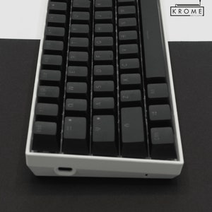 May include: A white mechanical keyboard with black keycaps. The keyboard has a minimalist design and features a USB-C port on the side.