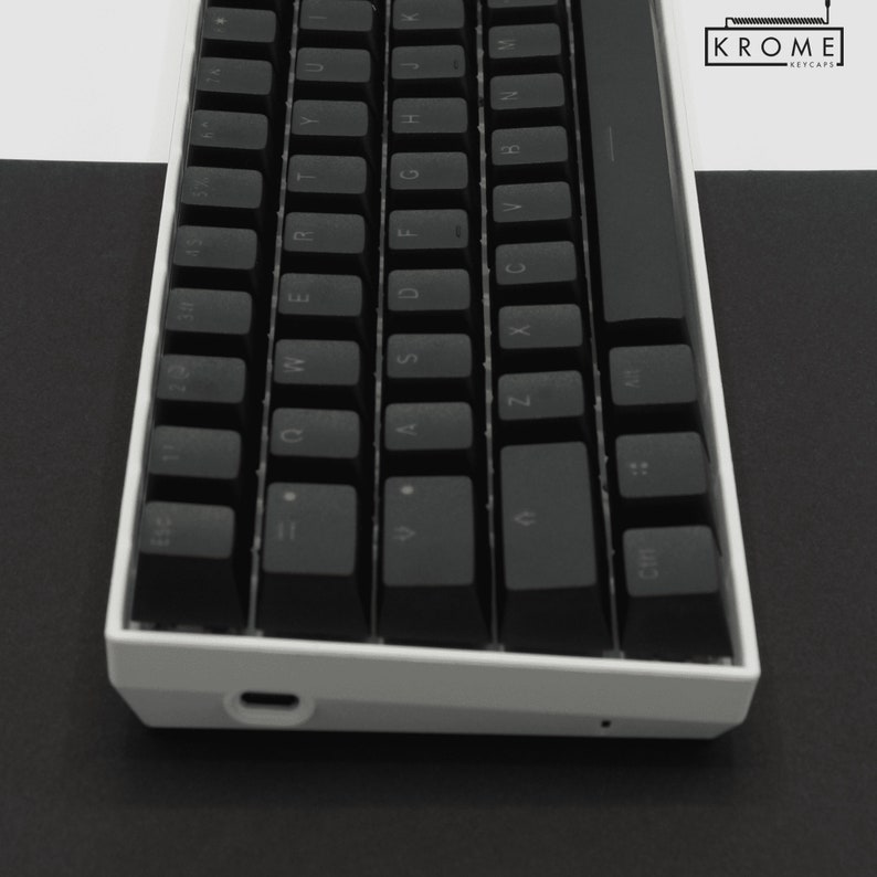 May include: A white mechanical keyboard with black keycaps. The keyboard has a minimalist design and features a USB-C port on the side.