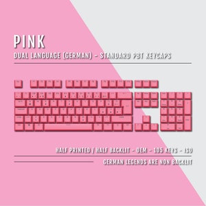 Könnte beinhalten: Eine pinkfarbene mechanische Tastatur mit deutschsprachigen Tastenkappen. Die Tastatur hat ein Standard-PBT-Tastenkappen-Layout mit 105 Tasten. Die Beschriftungen sind halb bedruckt und halb hinterleuchtet.