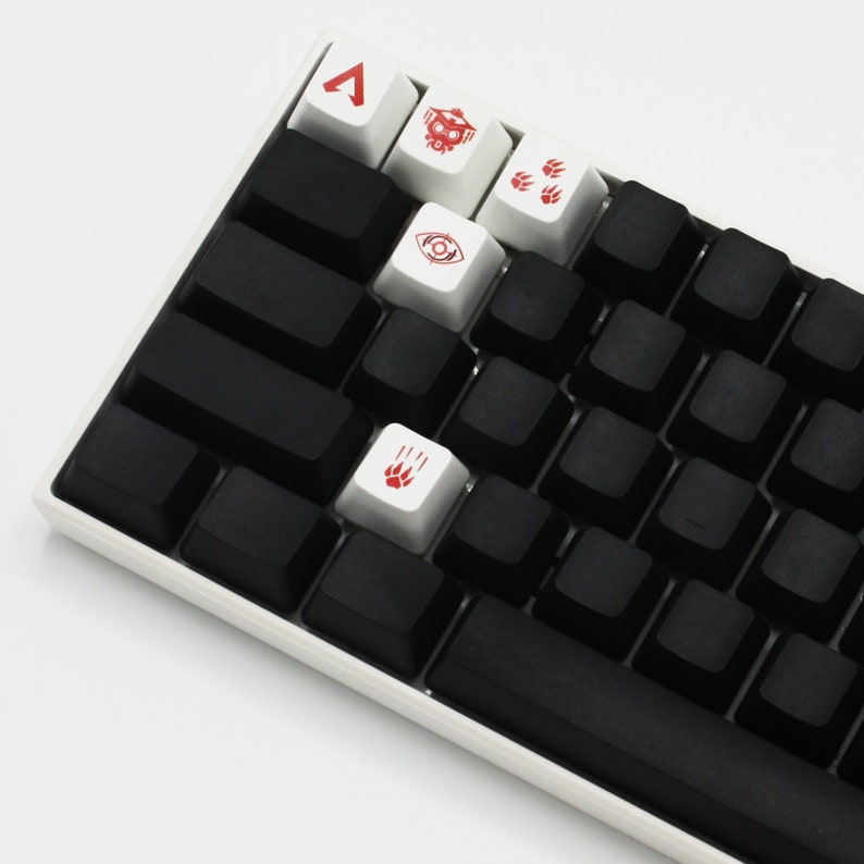 May include: A white mechanical keyboard with black keycaps and red and white keycaps with symbols. The symbols include a triangle, a skull, paw prints, and an eye.