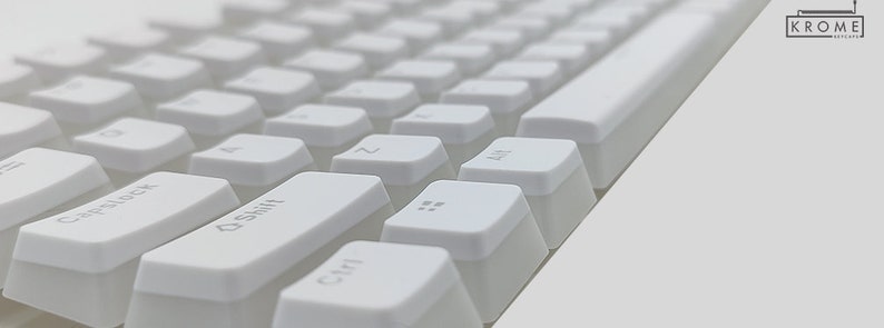 Op de afbeelding: Wit mechanisch toetsenbord met toetsen die zijn gelabeld met letters en symbolen. Het toetsenbord is schuin van onder links naar boven rechts.