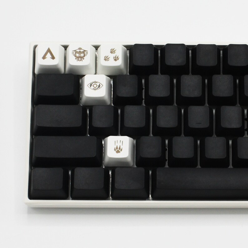 May include: A black mechanical keyboard with white keycaps featuring various symbols, including an arrow, a robot, paw prints, and an eye. The keyboard has a black space bar.