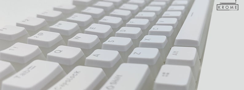 Op de afbeelding: Wit mechanisch toetsenbord met lege toetsen. Het toetsenbord heeft een standaard lay-out met functietoetsen, cijfertoetsen en lettertoetsen. Het toetsenbord is gemaakt van wit plastic en heeft een minimalistisch ontwerp.