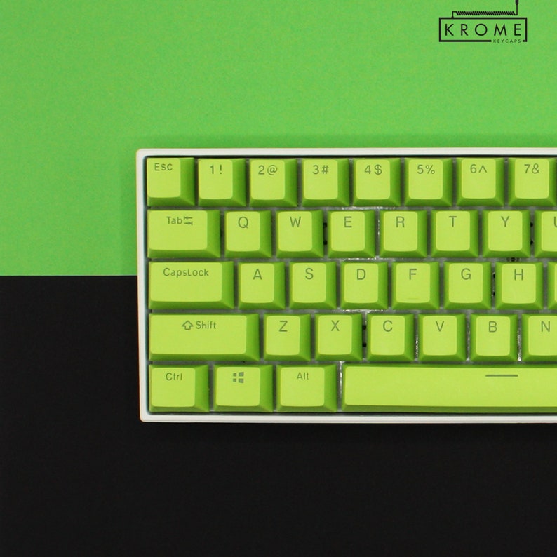 May include: A green and white keyboard with the letters 'KROME' and 'KEYCAPS' printed on the top right corner. The keyboard has a white frame and green keys with white lettering. The keys are labeled with the standard keyboard layout, including Esc, Tab, CapsLock, Shift, Ctrl, Alt, and the function keys.