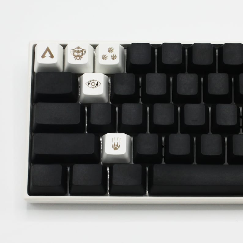 May include: A black mechanical keyboard with white keycaps featuring various symbols, including an arrow, a robot, paw prints, and an eye. The keyboard has a black space bar.