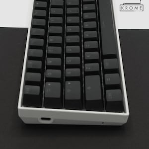 May include: A white mechanical keyboard with black keycaps. The keyboard has a minimalist design and features a USB-C port on the side.