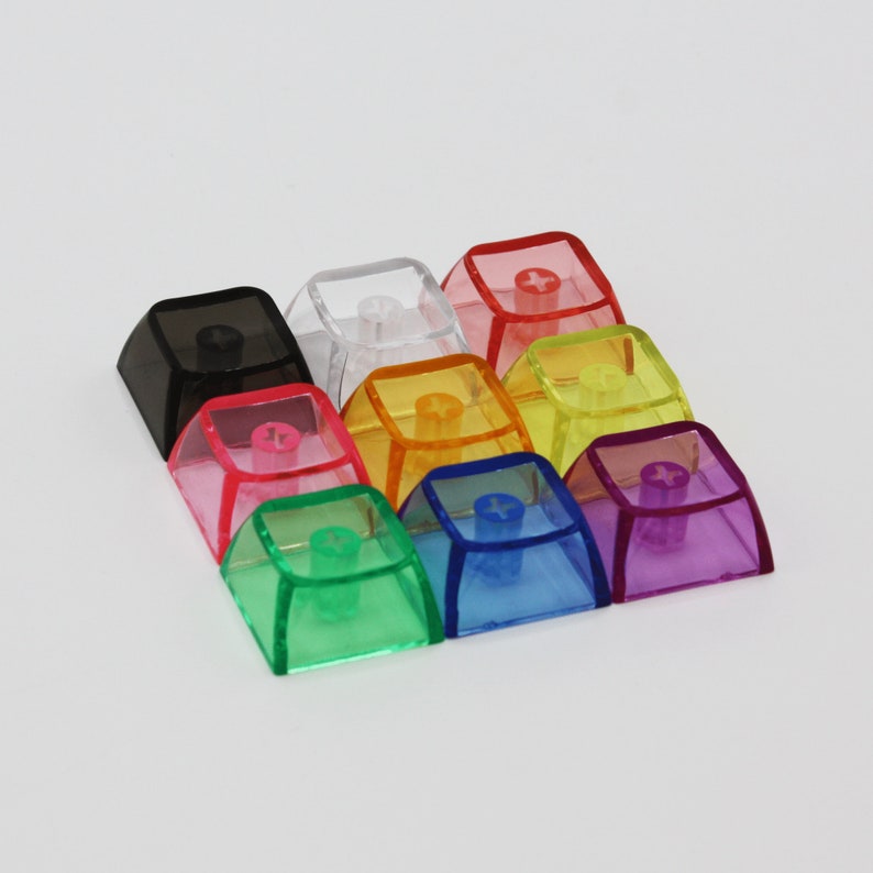 May include: Ten transparent keycaps in various colours, including black, red, orange, yellow, green, blue, and purple. The keycaps are square-shaped with a small, round, raised button in the centre.
