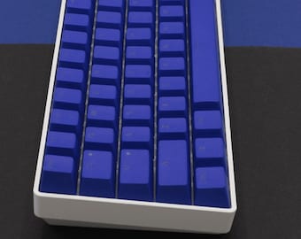 Könnte beinhalten: Eine weiße mechanische Tastatur mit blauen Tastenkappen. Die Tastatur hat einen weißen Rahmen und eine blaue Leertaste.